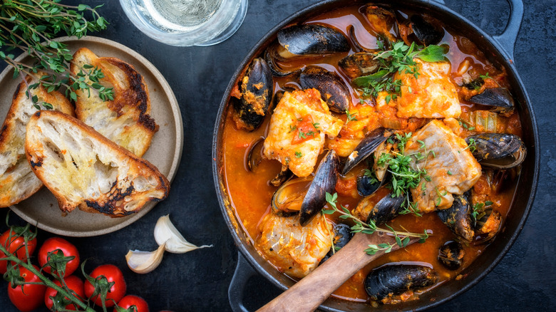 Seafood stew in pot with crusty bread
