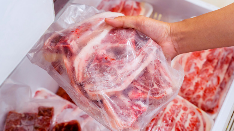 Person taking bag of frozen beef from freezer