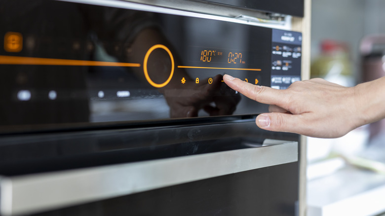 human hand setting temperature on an oven