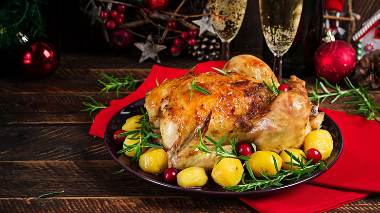 roasted turkey with rosemary, cranberries, and potatoes on holiday tablescape