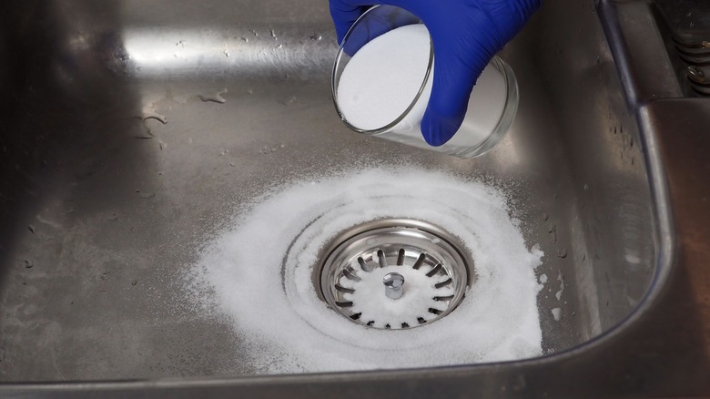 Person putting baking soda in a kitchen sink