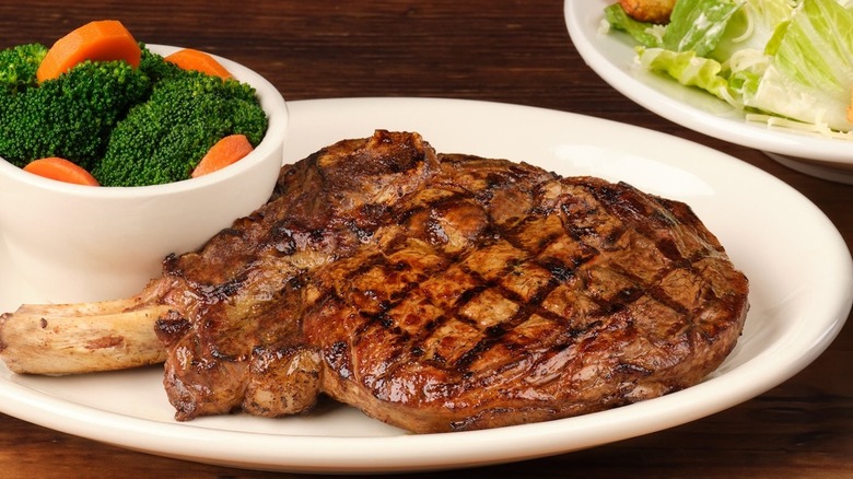 Texas Roadhouse's Bone-In Ribeye on a white plate with side of veggies