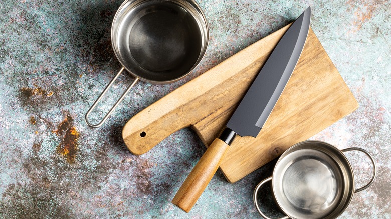 Chef's knife on cutting board beside pots