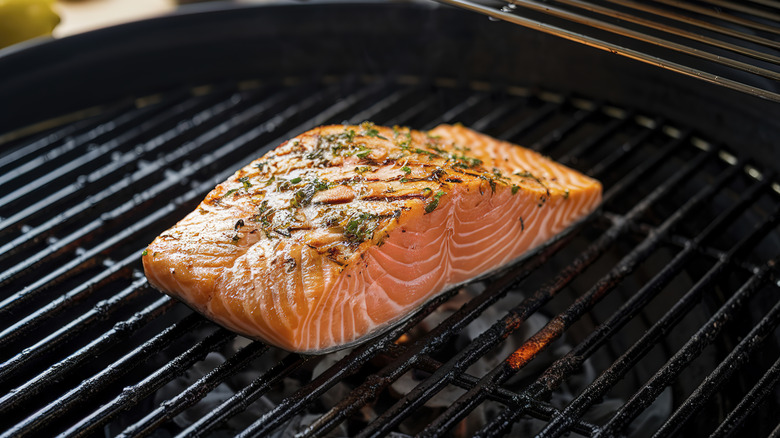 A seasoned salmon filet sits on a grill, roasting over low heat