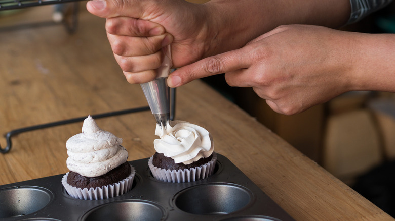 Piping a buttercream rosette onto a cupcake.