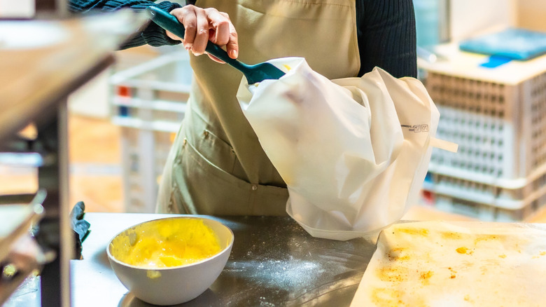 A baker filling a piping bag.