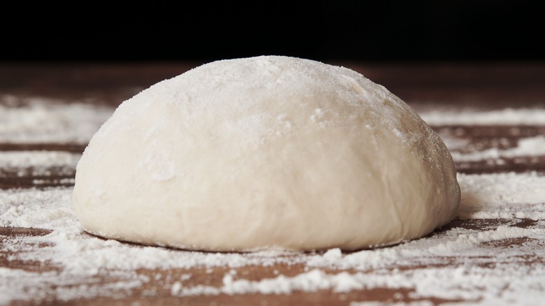 proofed dough ball on floured surface