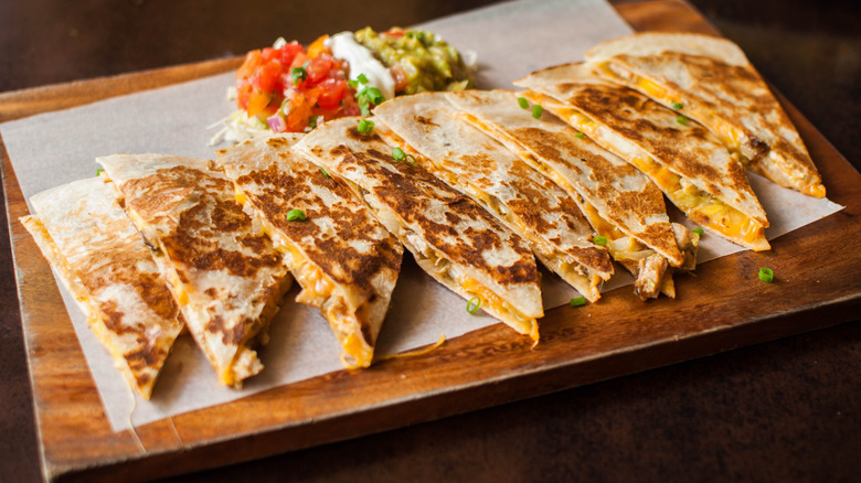 A row of chicken quesadillas on a wooden board