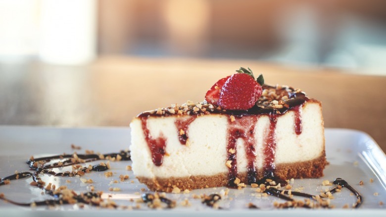 Slice of cheesecake with strawberries and chocolate drizzle 