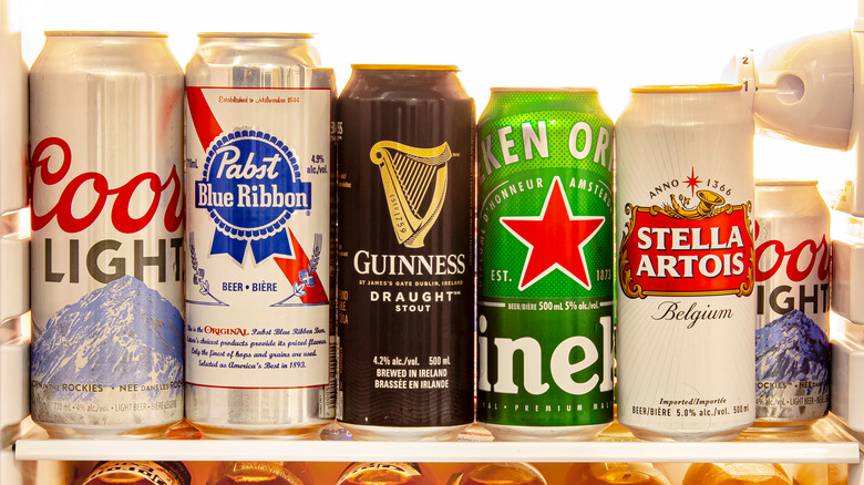 a row of mass-produced beer cans on a fridge shelf