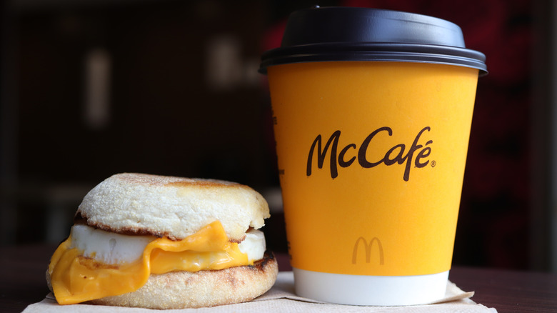 An egg McMuffin sits next to a McCafe coffee cup on a brown napkin