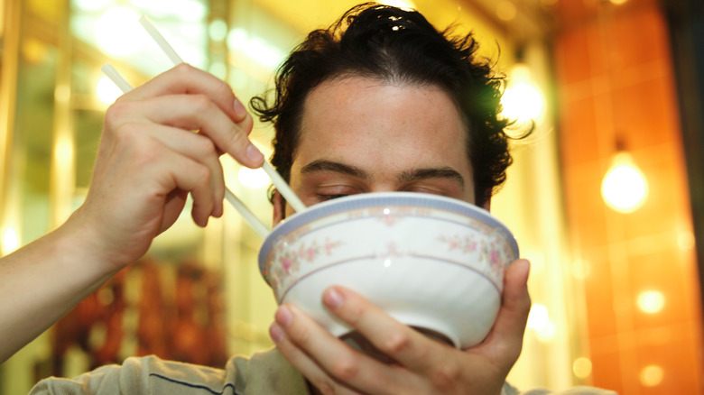 Man drinking noodle soup from bowl