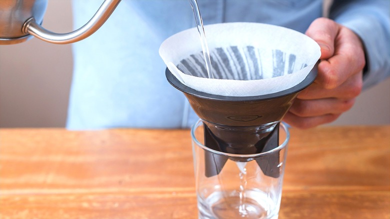 Hands pouring water through coffee filter