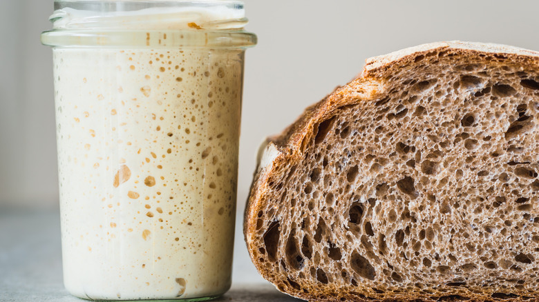 active sourdough in a jar beside loaf of bread