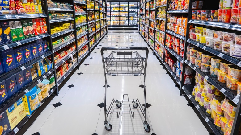 Grocery store aisle with empty shopping cart