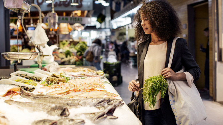 A shopper looks at a fish display in a grocery store