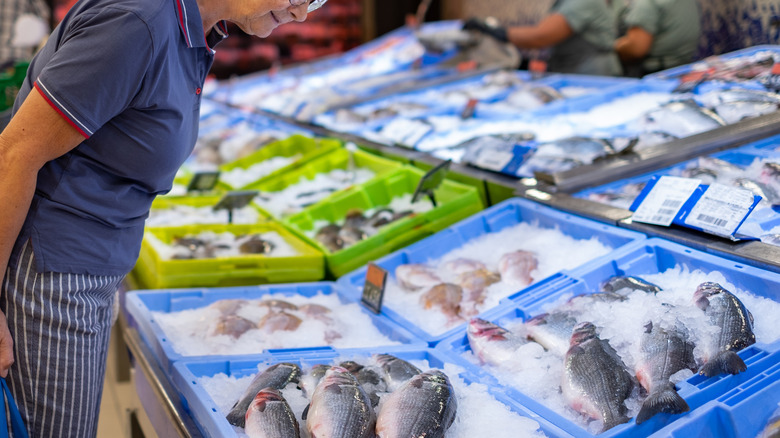 A shopper looks at fish displayed on ice in a supermarket