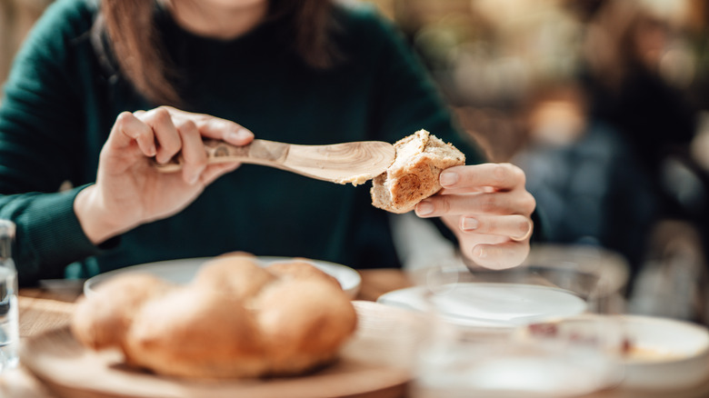 Woman spreading butter on bread with wooden spoon