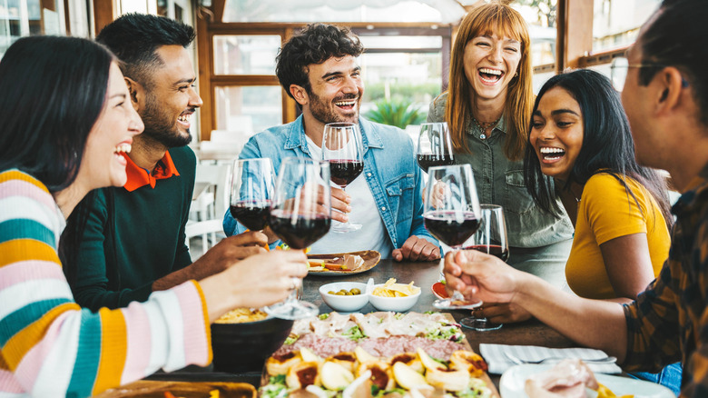 Group of people around a table with appetizers and red wine