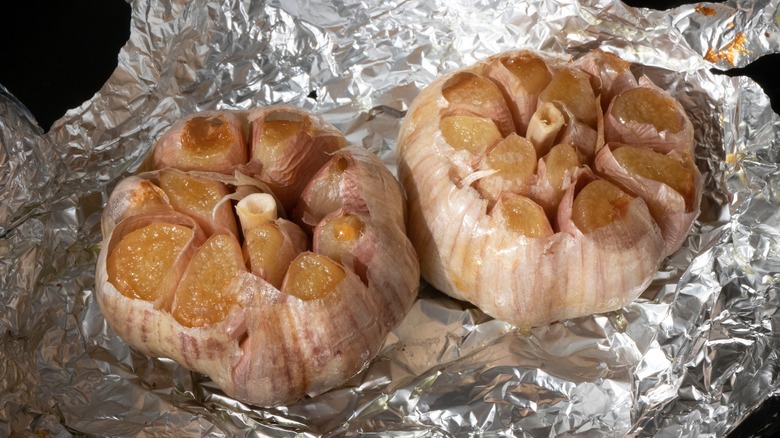 Two bulbs of roasted garlic on foil