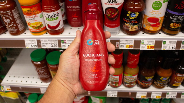 Hand holding a gochujang bottle at the grocery store