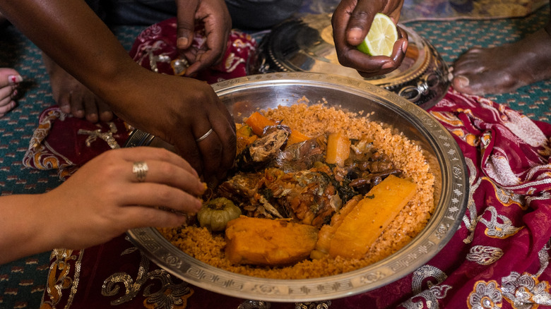Eating North African couscous dish by hands