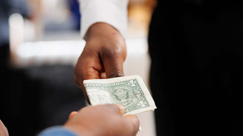 Closeup of a diner handing money to a server