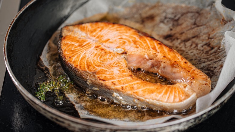 salmon and parchment paper in a frying pan