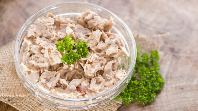 Small glass bowl of tuna salad with fresh parsley on top and on the side