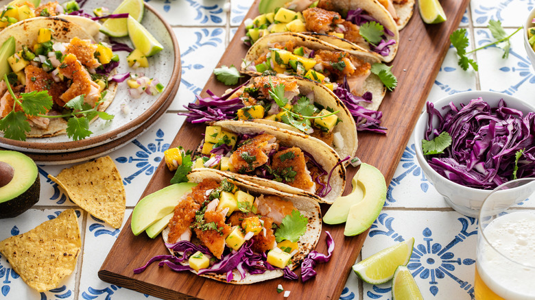 battered fish tacos with red cabbage and mango salsa on wooden board