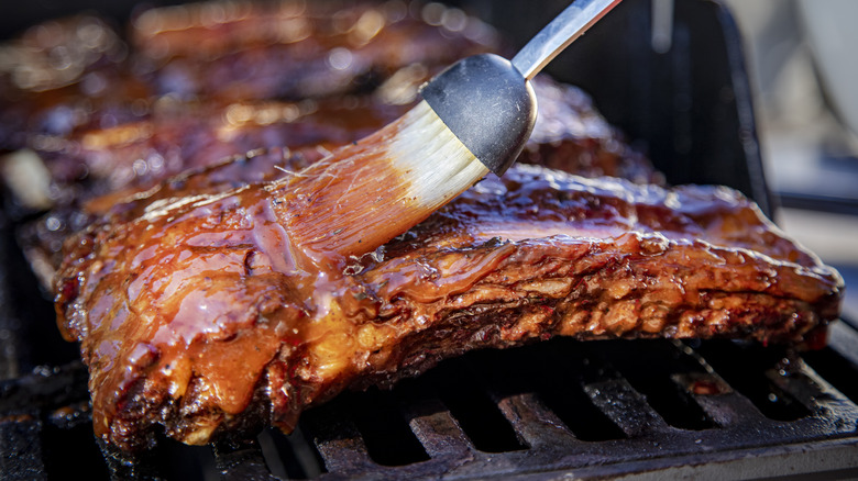 adding barbecue sauce to ribs