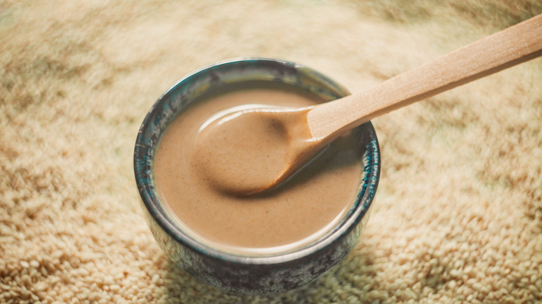 a bowl of smooth tahini with a wooden spoon