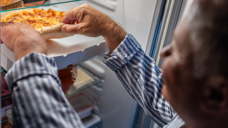 Person grabbing pizza from fridge