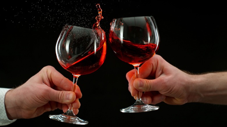 People clinking glasses of red wine