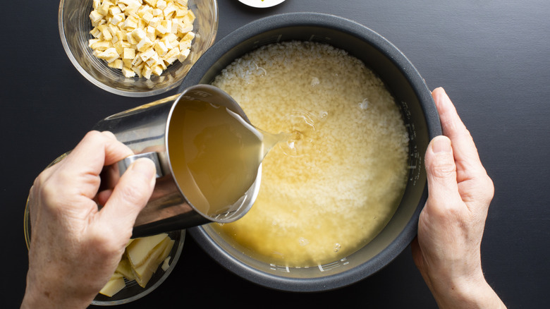 Pouring cooking liquid into pot of rice