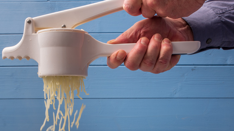 Hands using potato ricer