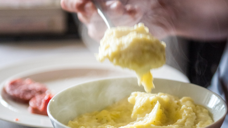 Hand spooning steamy mashed potatoes