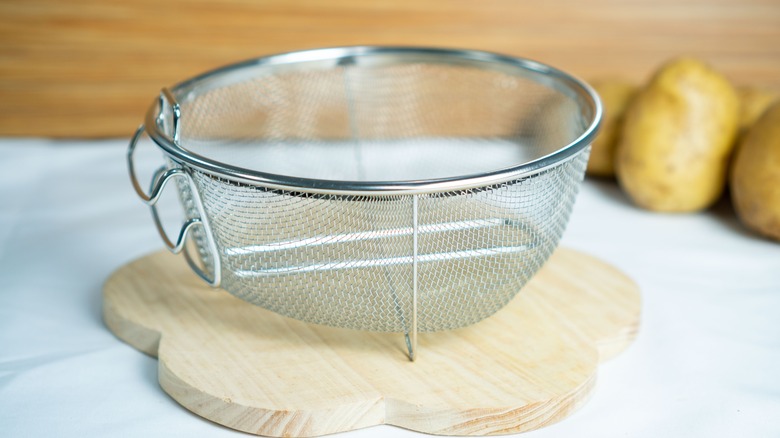 Fine mesh strainer bowl on wooden board