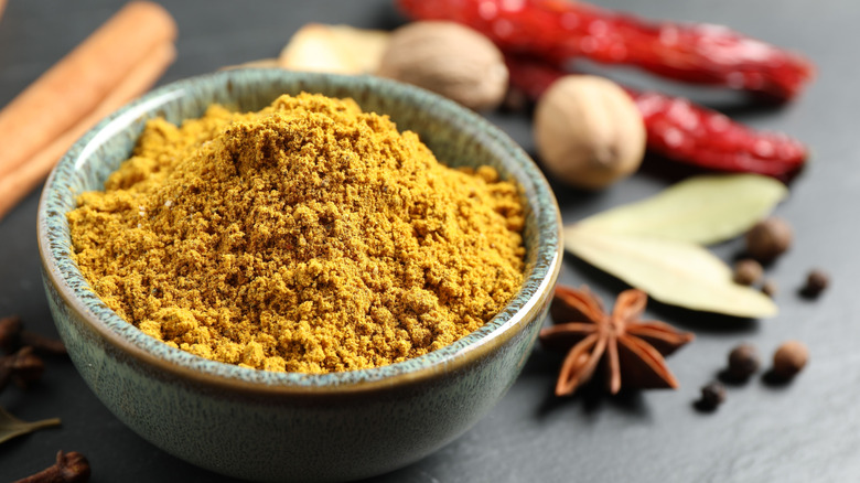 yellow curry powder in a small bowl surrounded by other spices