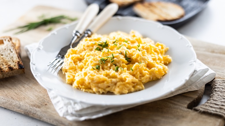 Fluffy scrambled eggs in a dish with knife and fork