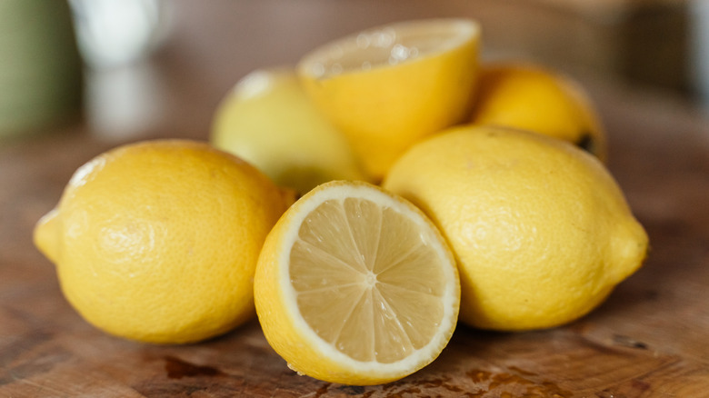 A pile of lemons on a cutting board