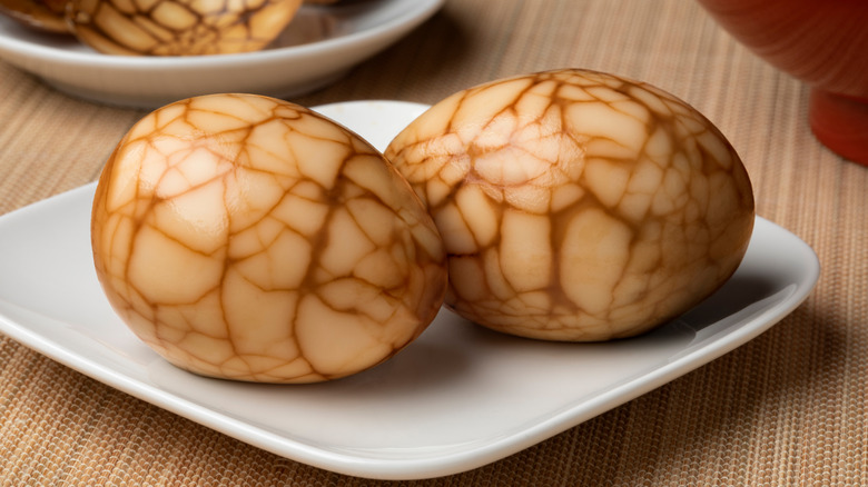 Two Chinese marbled tea eggs on a square white plate
