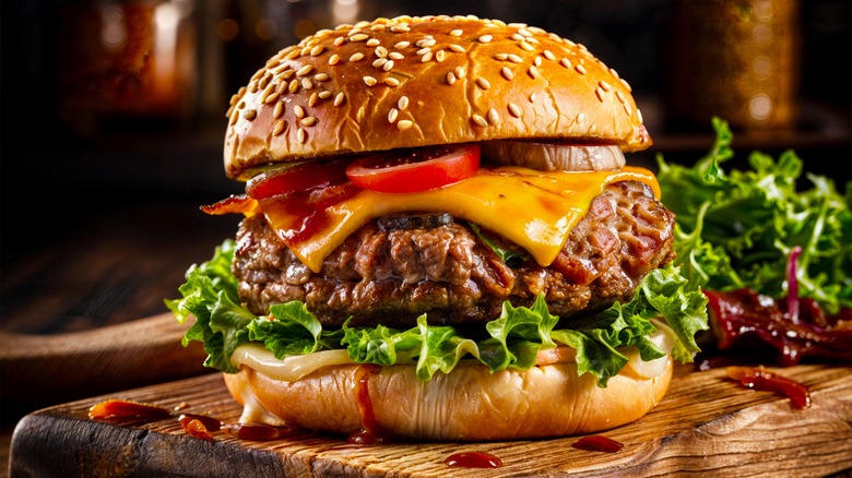 gourmet cheeseburger on sesame seed bun on wooden butcher block