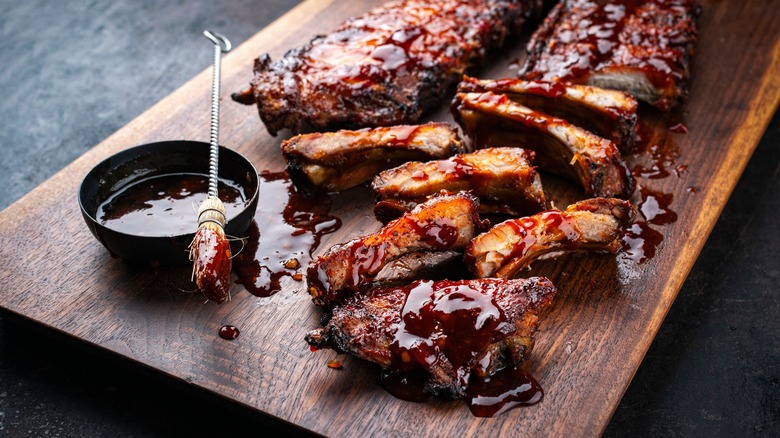 Meat slathered in barbecue sauce on wooden board