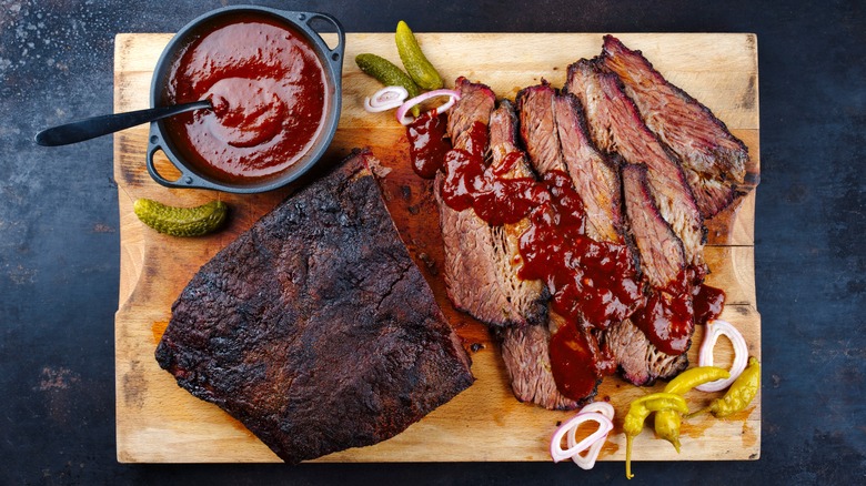 Brisket and barbecue sauce on wooden cutting board