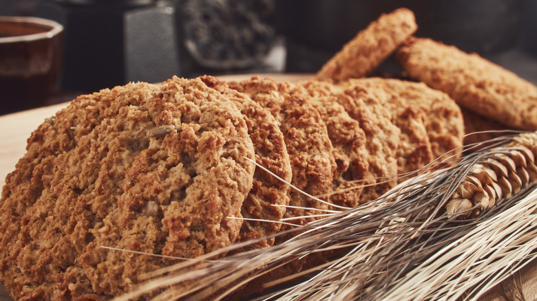 Close up of gingersnaps in a row in a wooden and stray basket with a skinny pinecone. All on a table with blurred kitchen or dining in the background.