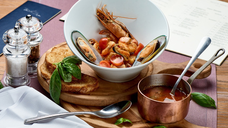 Bouillabaisse with seafood in a dish and broth in a pan