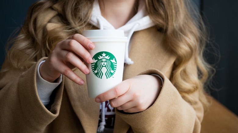 woman holding Starbucks takeaway cup