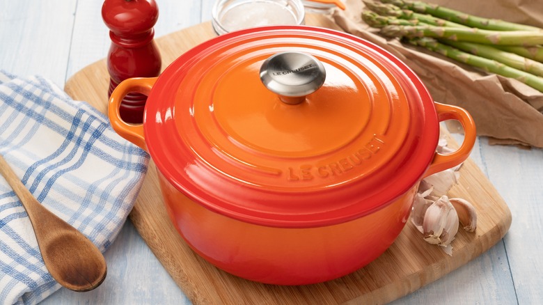 orange enameled dutch oven on cutting board