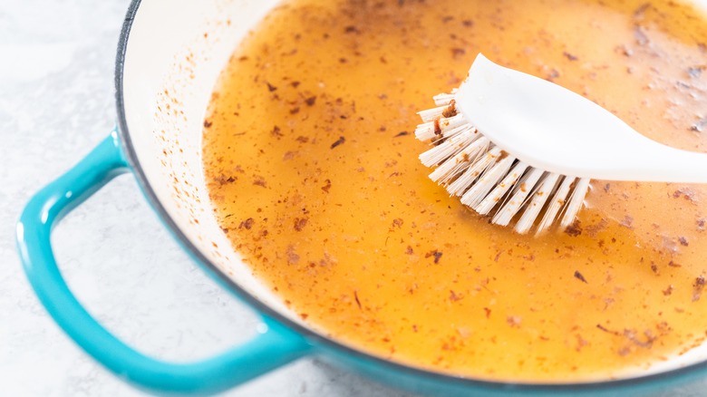 A brush and an enameled cast iron pot